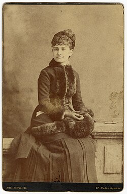 Mary Harrison McKee sitting while wearing a dress