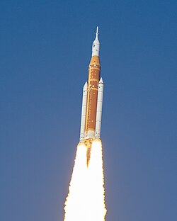 A rocket trailing flame against a blue sky